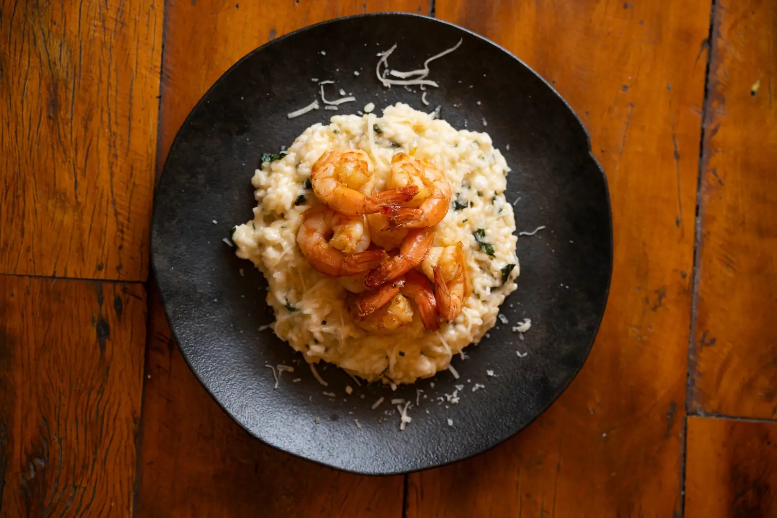 Risoto com camarões servido em prato de cerâmica escura